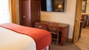 Ein Hotelzimmer mit Bett, Schreibtisch, Stuhl, Kleiderschrank und Fernseher an der Wand.