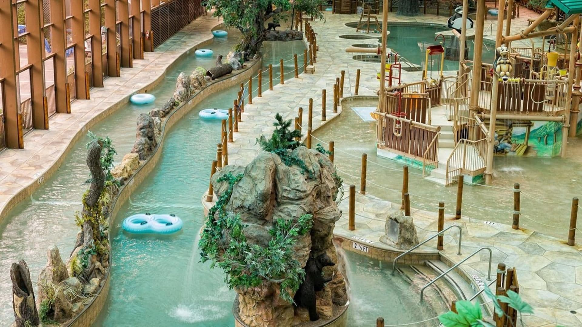 Parque acuático interior con toboganes, flotadores hinchables y una estructura de escalada con forma de oso.