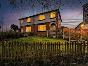 Een huis met twee verdiepingen, een veranda en een houten hek.