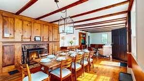 Un coin repas agrémenté d’une cheminée, de murs en bois et d’une grande table dressée pour six personnes.