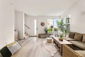 Un salon moderne avec un canapé, une table basse et un escalier menant à une autre pièce.