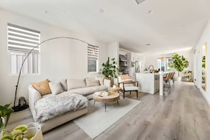 Un salon moderne comprenant un canapé, une table basse et un coin repas avec des chaises.