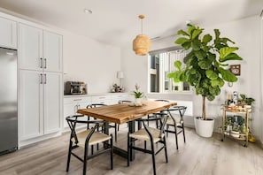 Une cuisine moderne avec des meubles blancs, une table à manger en bois et des chaises noires.