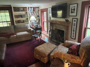 A cozy living room with a fireplace, bookshelves, a television, and comfortable seating.