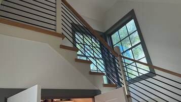 A staircase with a view of the outdoors through a window, leading to a storage area with boxes and baskets.