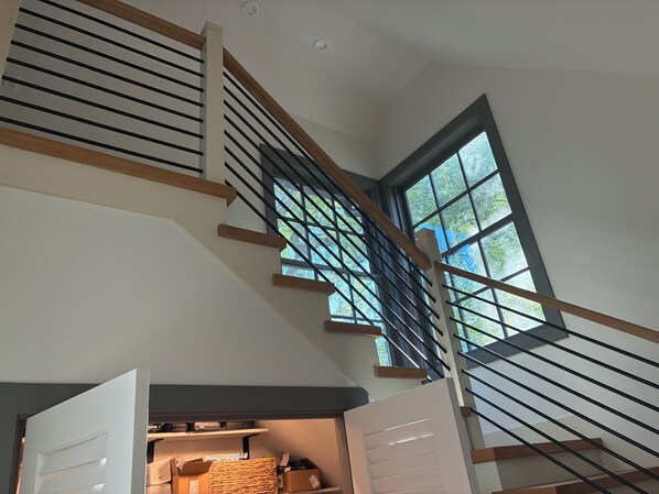 A staircase with a view of the outdoors through a window, leading to a storage area with boxes and baskets.