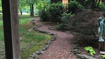 A gravel path leading to a wooden cabin surrounded by trees.