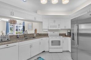 A modern kitchen with white cabinetry, stainless steel appliances, a built-in microwave, and a dishwasher. - Resort‑style 3BR Naples condo w/ tennis, pickle, pool, spa, tiki bar & fitness. (Naples)