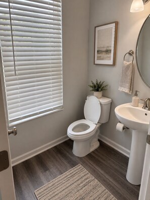 A bathroom with a toilet, sink, and window with blinds. - The Cozy Retreat Spacious Townhome Getaway in Charlotte (Charlotte)