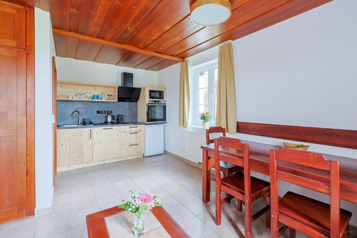 Una cucina compatta con mobili in legno, un forno a microonde e un piano cottura.