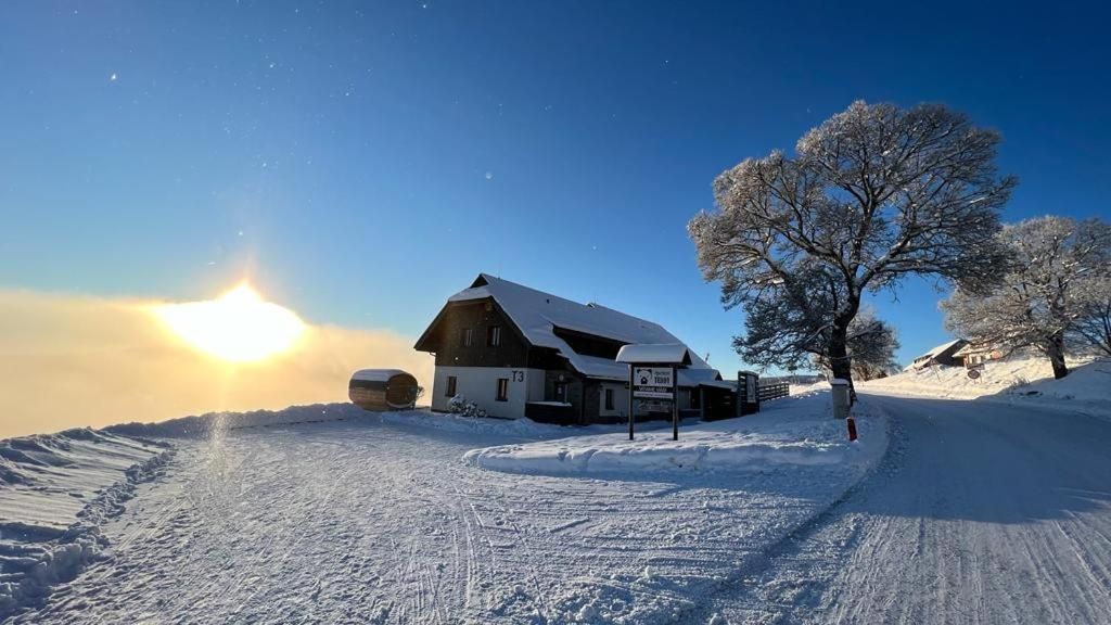 A snow-covered landscape with a building that has a sloped roof and a sign indicating a restaurant.