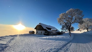 A snow-covered landscape with a building that has a sloped roof and a sign indicating a restaurant.