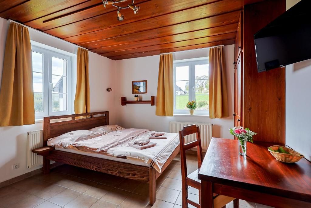 Une chambre à coucher avec un lit en bois, une table en bois et une fenêtre avec des rideaux.