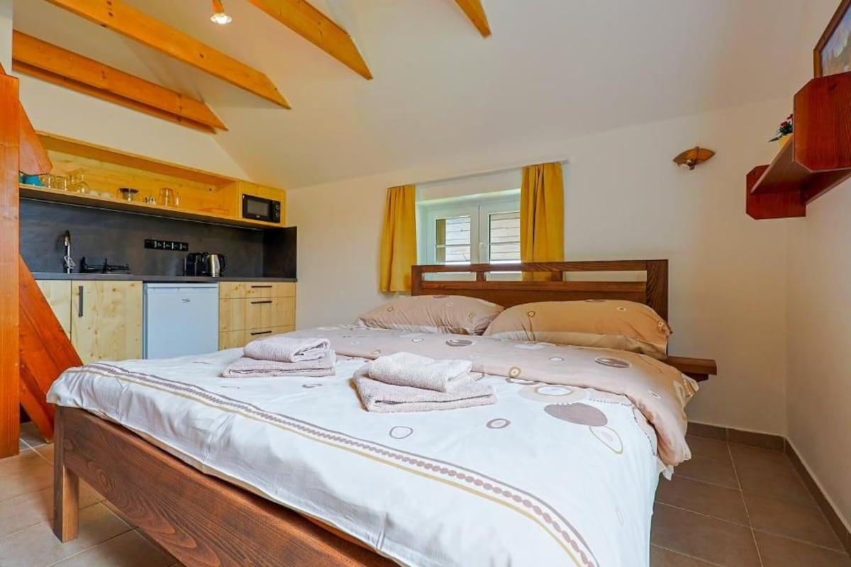 Una camera da letto con un letto in legno, un angolo cottura integrato e una finestra con tende.