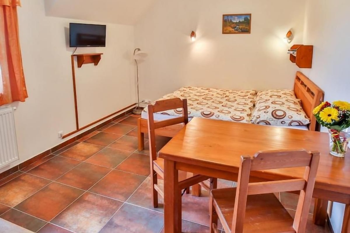 Un'area pranzo con un tavolo e sedie, un televisore montato a parete e un quadro appeso.