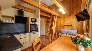 Een houten interieur met keuken, eethoek en een vide.