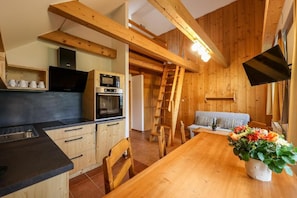 A wooden interior with a kitchen, dining area, and a loft space. - Aparthotel TEDDY (Kvilda)