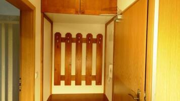 Een kamer met een houten kast, een deur en een betegelde vloer.