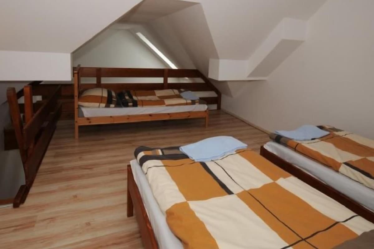 Una stanza con soffitto spiovente, letti a castello in legno e un lucernario.
