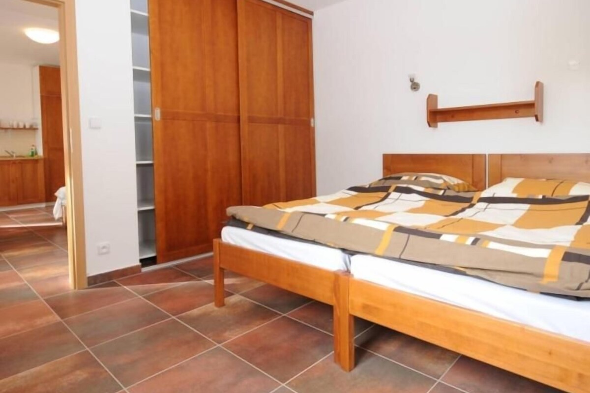 A bedroom with a bed, wooden wardrobe, and a bathroom visible in the background.