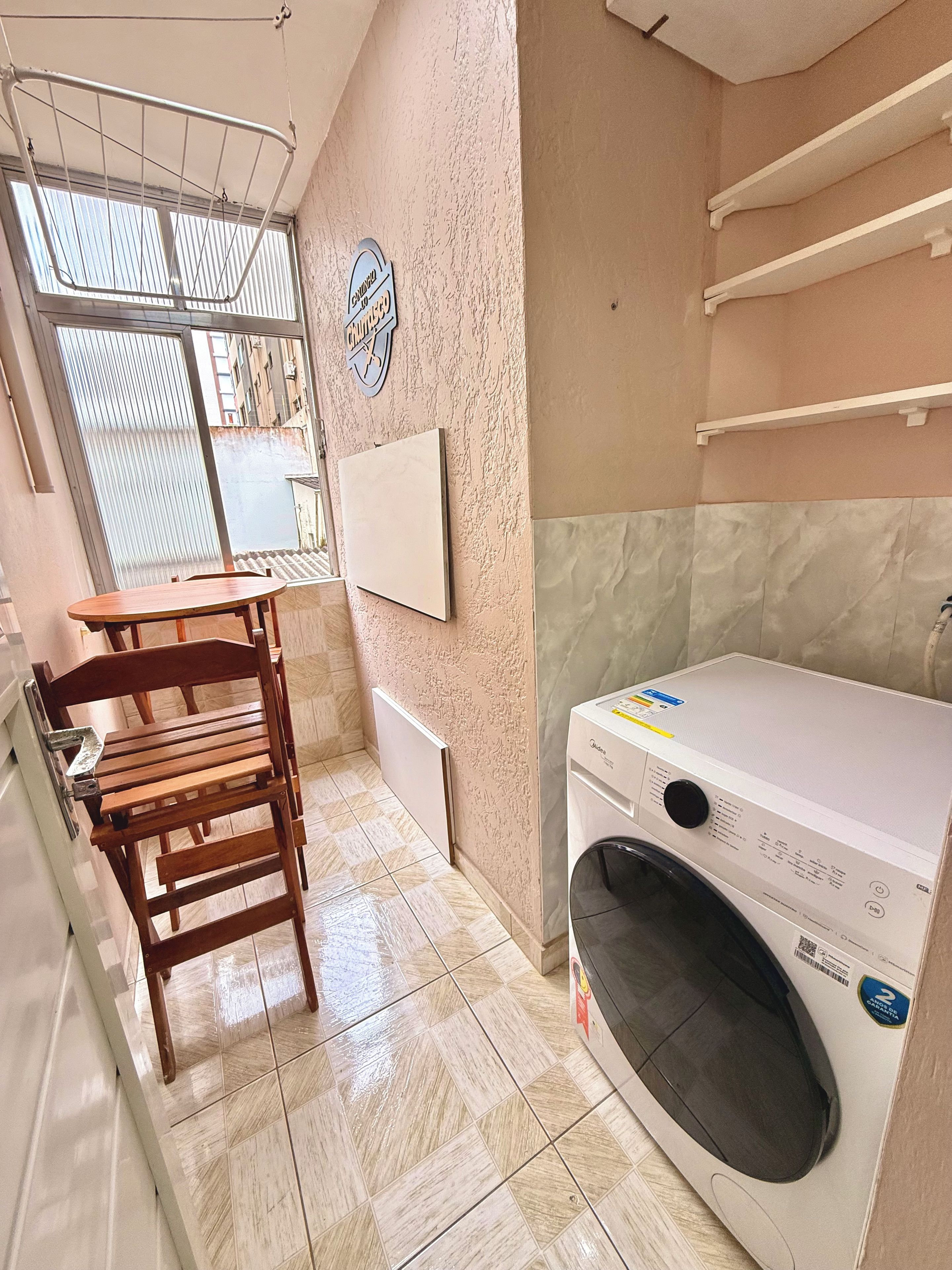 A laundry room with a washing machine, a drying rack, and a chair.