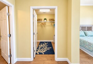 A hallway with a blue carpet leading to a bedroom with a bed. - Luxury Coastal Condo, Pool, Hot Tub, 11th Floor (Panama City Beach)