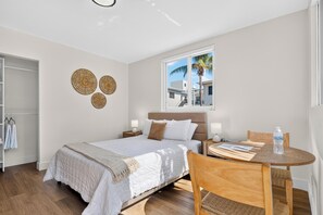 Een hotelkamer met een bed, nachtkastjes, een raam met uitzicht, een ronde houten tafel en een stoel.