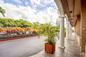 A hotel corridor with a view of a road lined with trees and a mountain in the background. - New Lahaina Shores 5th Floor  2 Lanai's Ocean view & Mountain View Corner unit (Lahaina)
