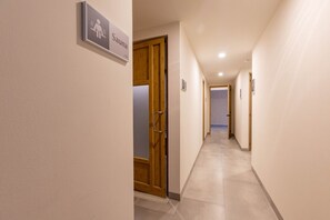 Ein Flur mit Hinweisschild auf eine Sauna, Holztüren und einem gefliesten Boden.