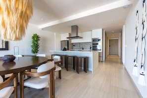 A modern kitchen with a central island, white cabinetry, and stainless steel appliances. - Pedregal Horizon | Views & Private Beach Access (Cabo San Lucas)
