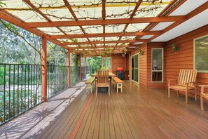Une terrasse en bois agrémentée d’une pergola, de mobilier d’extérieur et offrant une vue sur la verdure environnante.