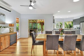 A modern kitchen with a dining area, wooden flooring, and a ceiling fan. - Moreton Bay Acreage Retreat Pool & Fireplace (Ransome)
