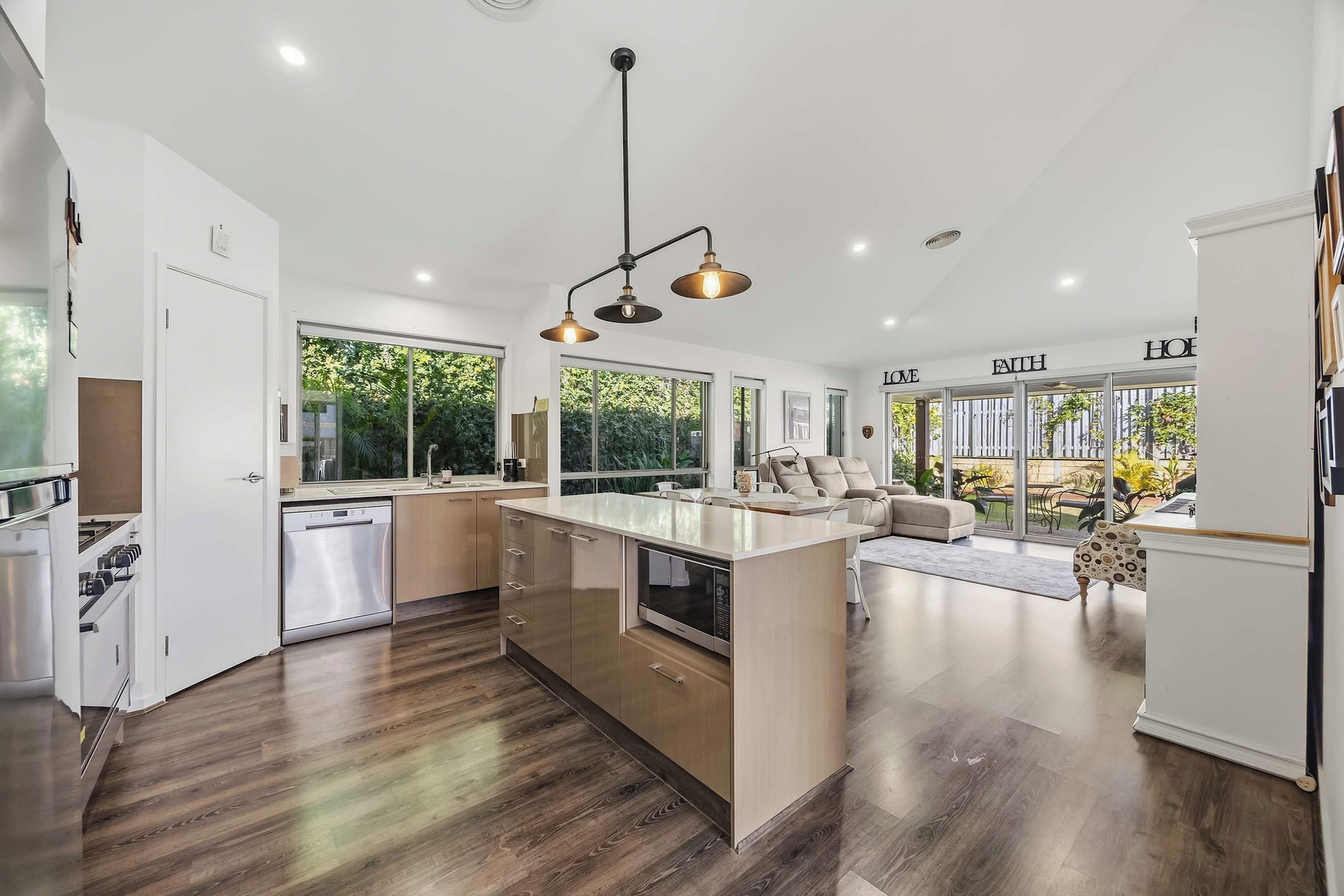 A modern kitchen with a central island, built-in appliances, and a dining area with a sofa and table.