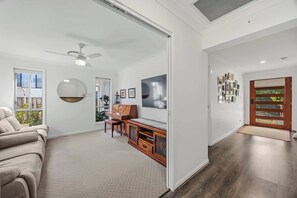 Ein geräumiges Wohnzimmer mit einer Couch, einem Klavier und einem Fernseher.