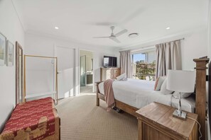 Ein Hotelzimmer mit Bett, Nachttisch, Fernseher und Deckenventilator, mit Blick ins Freie.