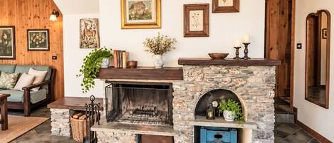 A cozy living room with a stone fireplace, a sofa, and various framed artworks on the walls.