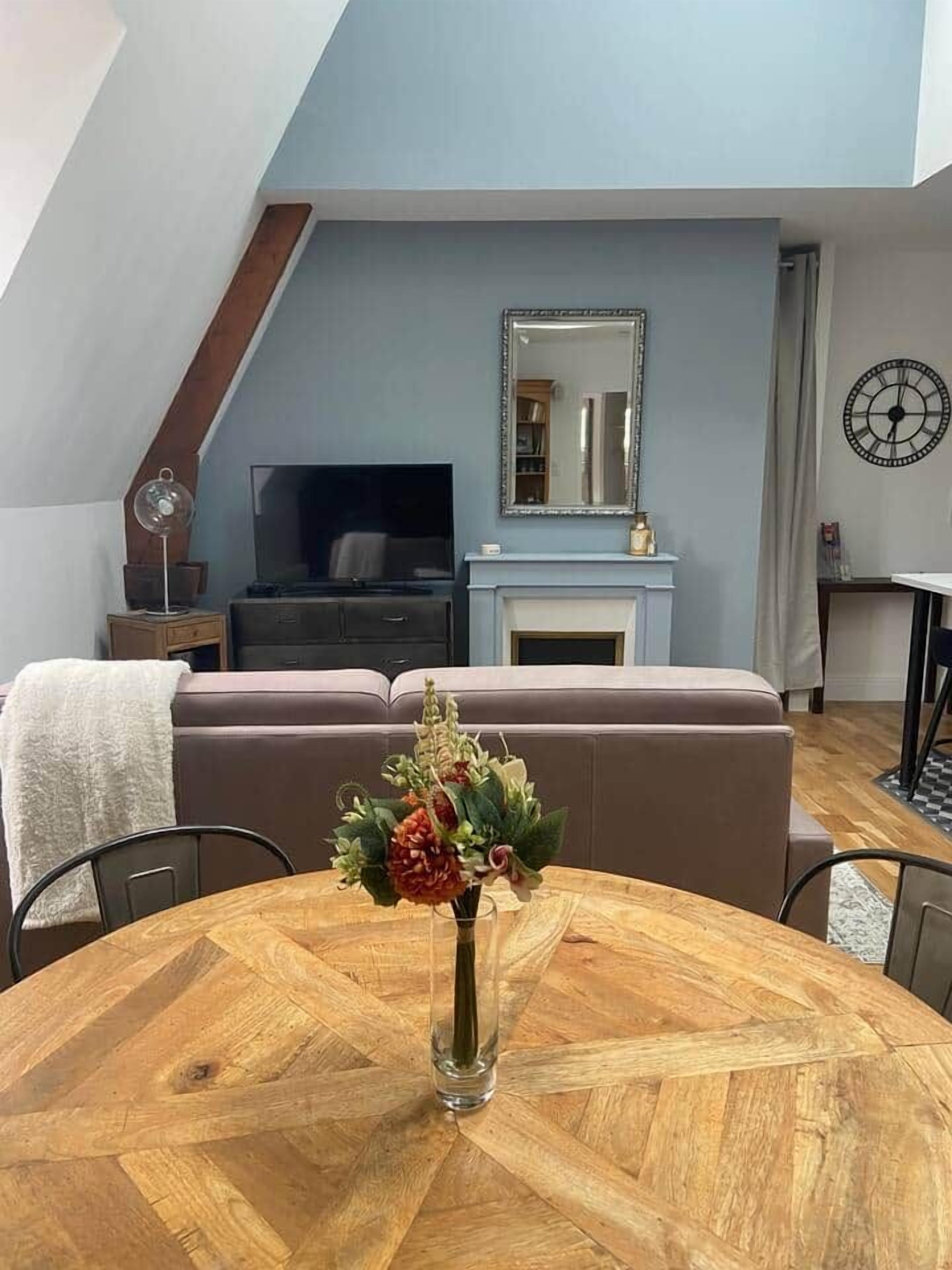 A living room with a round wooden table, a sofa, a fireplace, and a television.