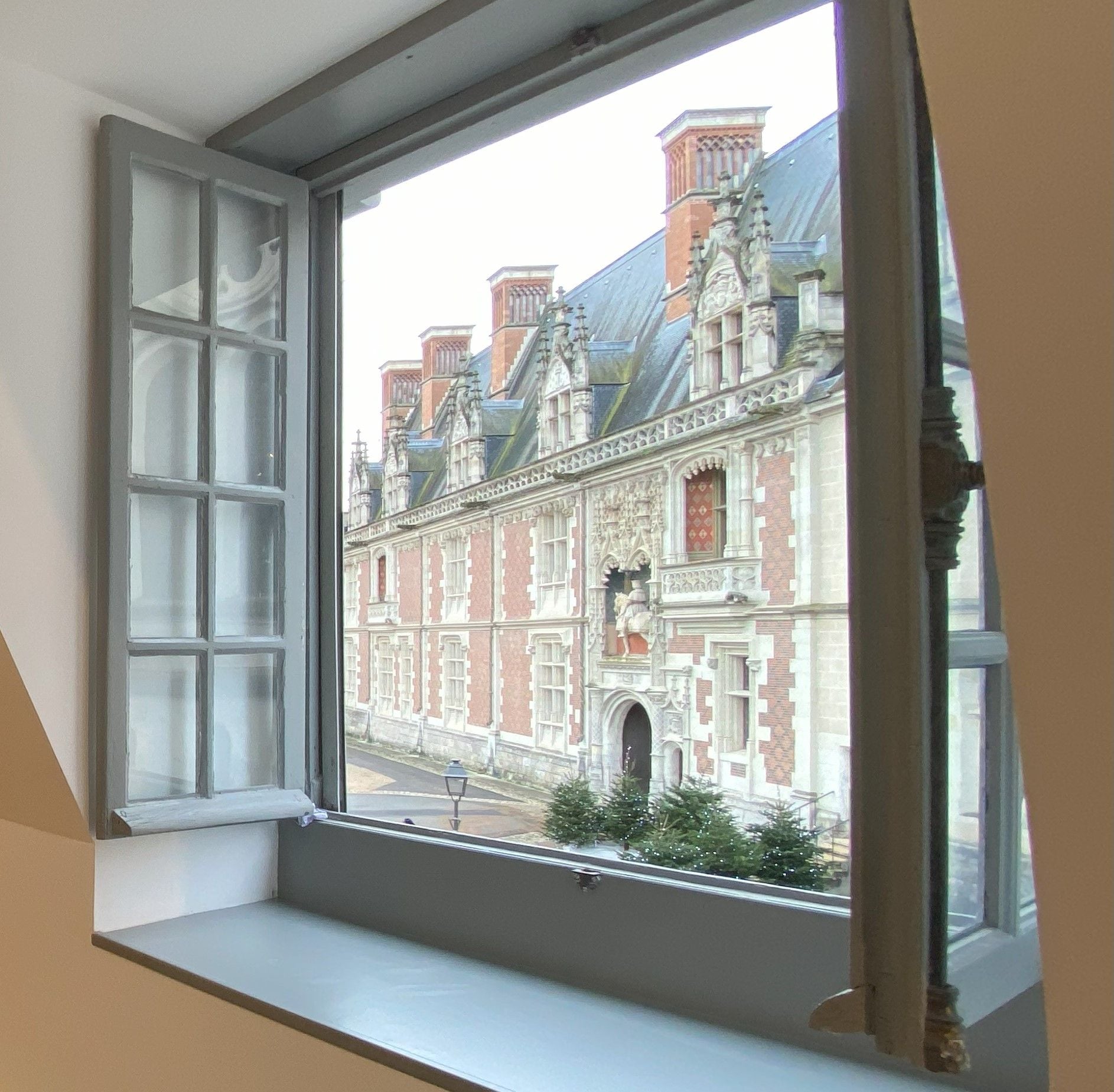 Una ventana con vistas a un edificio histórico de arquitectura ornamentada.