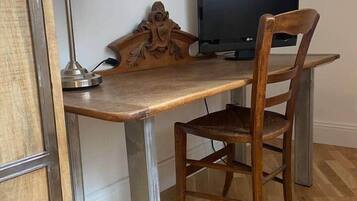 A wooden desk with a metal lamp and a television.