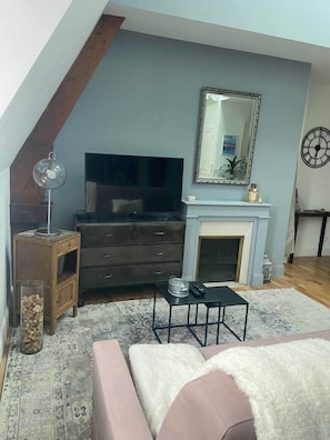 Una sala de estar con televisor, chimenea y un reloj en la pared.