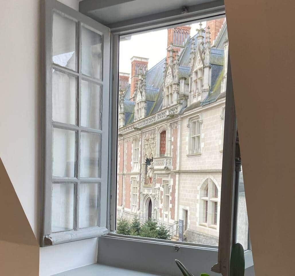 Una ventana con vistas a un edificio histórico de arquitectura ornamentada.