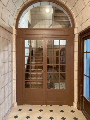 A brown double door with glass panels, leading to a staircase. - «Cathédrale» 5* castle-facing Suite, 7 guests (Blois)