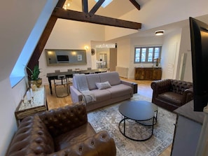 A loft-style living space with exposed wooden beams, a sofa, a coffee table, and a television. - «Cathédrale» 5* castle-facing Suite, 7 guests (Blois)
