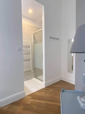A room with a wooden floor, a glass shower enclosure, a white door, and a light fixture on the ceiling. - «Duchesse Anne» 5* castle-facing Suite, 8 guests (Blois)