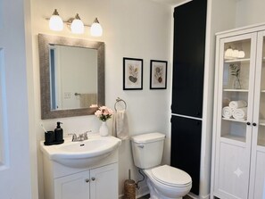 A bathroom with a white sink, a toilet, and a cabinet with glass doors. - Parkwood Nest | 2BR Home Base for Cape Breton (Sydney)