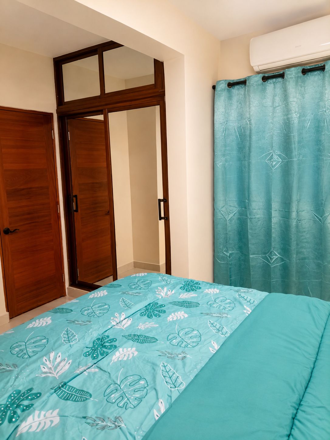 A bedroom with a bed, a wardrobe, and a curtain.