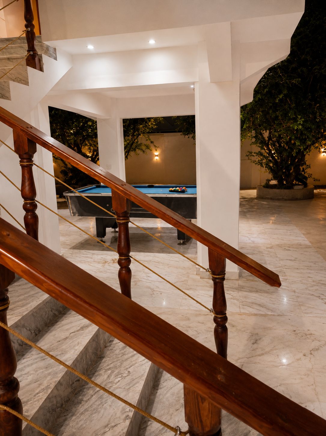 A marble staircase leading to a pool area with a wooden railing.