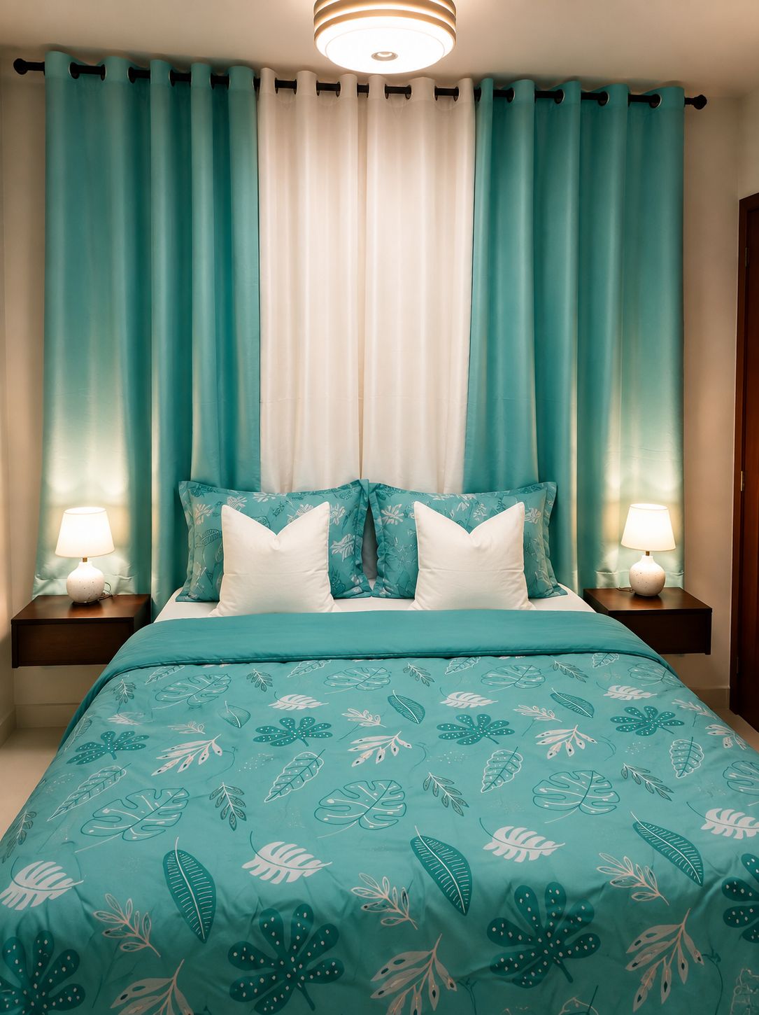 A bedroom with a bed, two bedside tables with lamps, and a window with curtains.