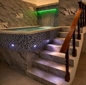 A spa area with a mosaic-tiled hot tub adjacent to marble stairs.