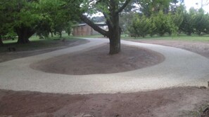 A landscaped area with a tree in the center, surrounded by a circular gravel path. - Tabletop Farm - Pool - Tolmie (Tolmie)